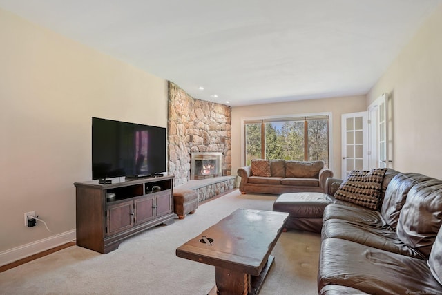 living area featuring a fireplace, light colored carpet, and baseboards