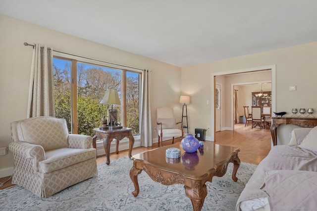 living area with a chandelier, light wood finished floors, and baseboards