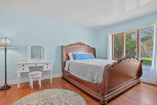 bedroom with baseboards, visible vents, and wood finished floors
