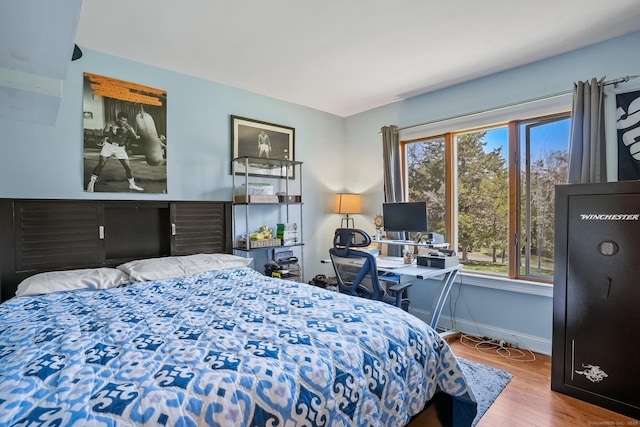 bedroom with baseboards, wood finished floors, and multiple windows