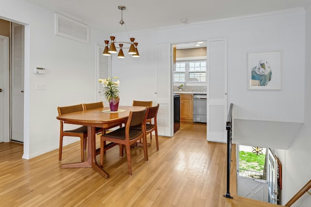 dining area featuring visible vents, crown molding, baseboards, light wood finished floors, and a chandelier