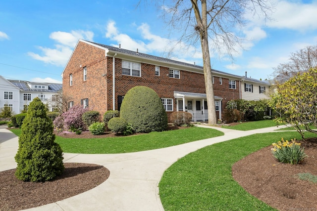 exterior space with brick siding and a front yard