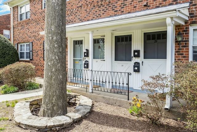 entrance to property with covered porch and brick siding