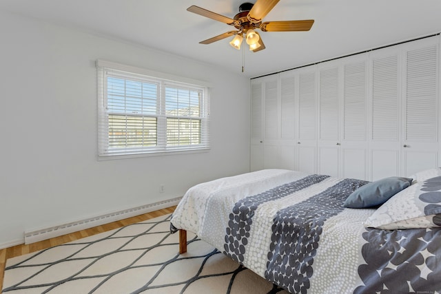 bedroom with baseboards, a ceiling fan, a baseboard heating unit, and wood finished floors