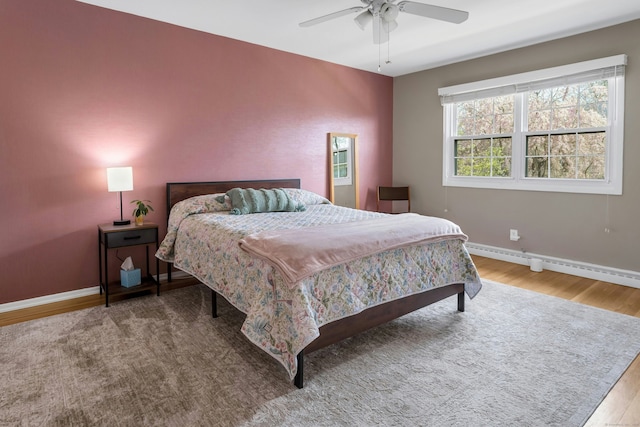bedroom featuring baseboards, a ceiling fan, a baseboard heating unit, and wood finished floors