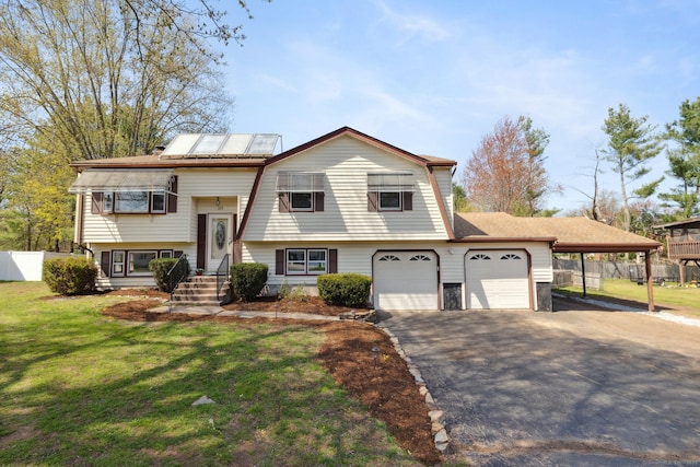raised ranch with aphalt driveway, fence, and a front lawn