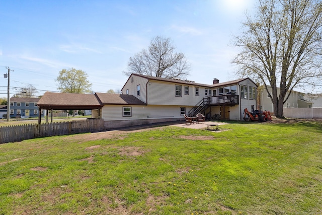 rear view of property with stairs, an outdoor fire pit, fence, and a yard