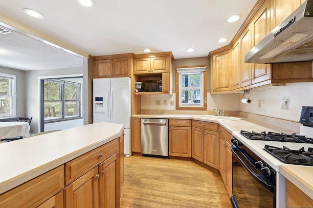 kitchen featuring under cabinet range hood, a sink, black appliances, and light countertops