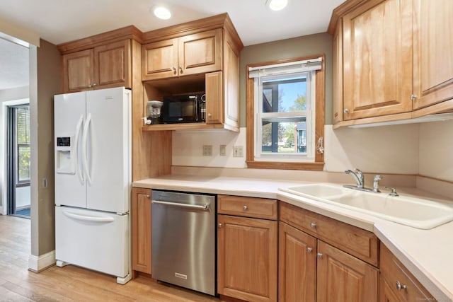kitchen featuring black microwave, a sink, light wood finished floors, white fridge with ice dispenser, and stainless steel dishwasher