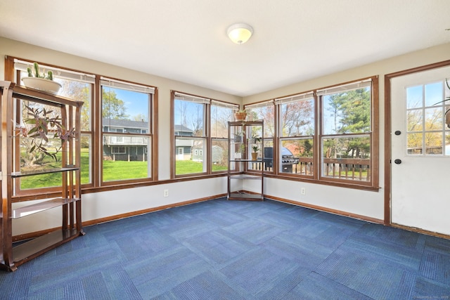 unfurnished sunroom featuring carpet floors and baseboards