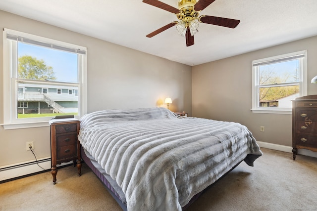 carpeted bedroom featuring baseboards, ceiling fan, and a baseboard radiator