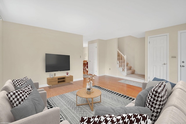 living area with baseboards, stairs, and wood finished floors