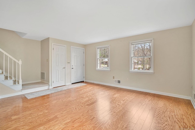 interior space featuring baseboards, visible vents, stairway, and light wood-type flooring