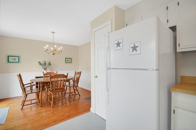 dining room with an inviting chandelier and a wainscoted wall