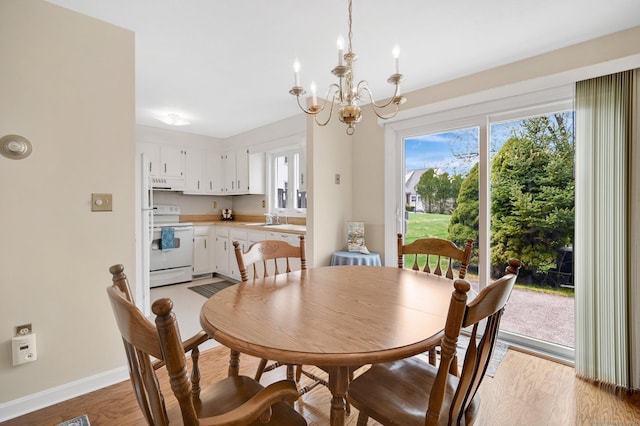 dining space featuring baseboards, light wood finished floors, and a chandelier