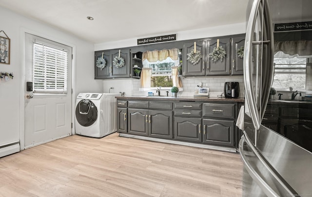 laundry area featuring a sink, light wood-style flooring, and a baseboard heating unit