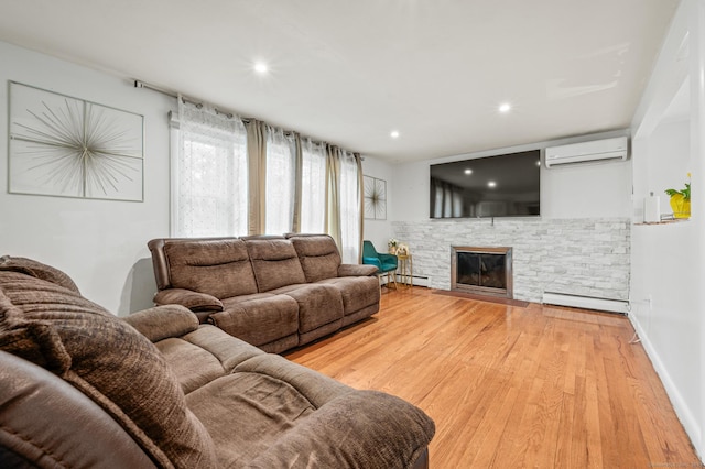 living room with light wood-style floors, a baseboard heating unit, a wall mounted AC, and a fireplace