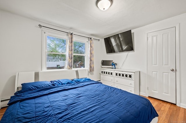 bedroom featuring wood finished floors and a baseboard radiator