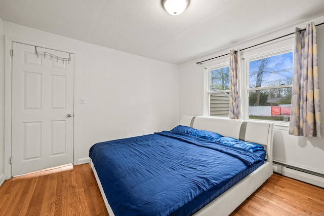 bedroom featuring baseboard heating and wood finished floors
