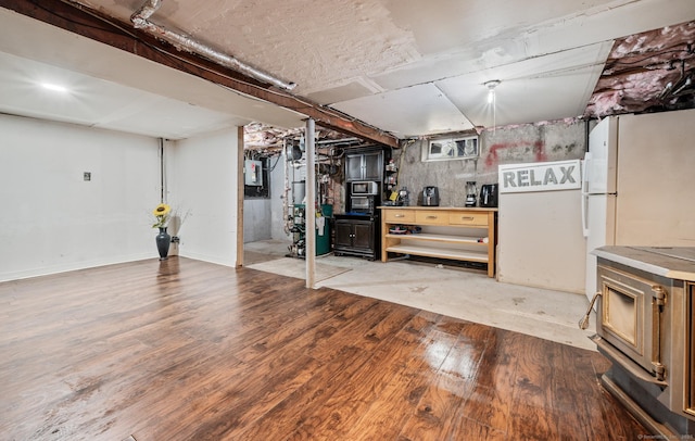 unfinished basement with light wood-style floors and freestanding refrigerator