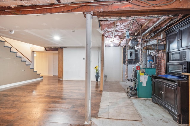 unfinished basement with baseboards, light wood-style flooring, stairs, and a toaster