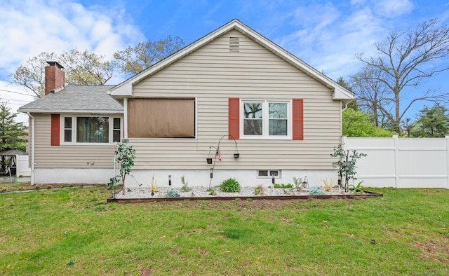 exterior space with fence, a chimney, and a yard