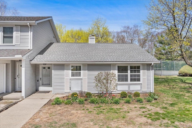 view of front of home featuring a front lawn, a shingled roof, and a chimney