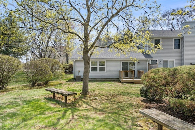 rear view of property with a lawn, a deck, and cooling unit