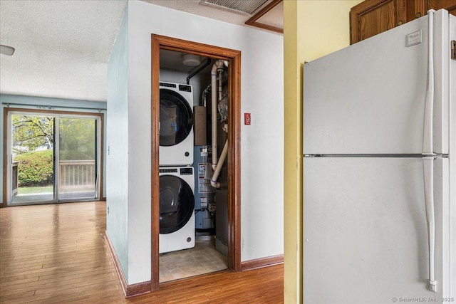 laundry room with stacked washer / dryer, laundry area, wood finished floors, and baseboards