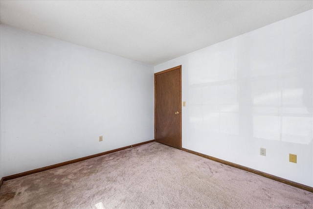 carpeted spare room featuring baseboards