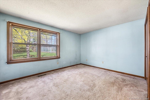 unfurnished room featuring baseboards, visible vents, a textured ceiling, and carpet