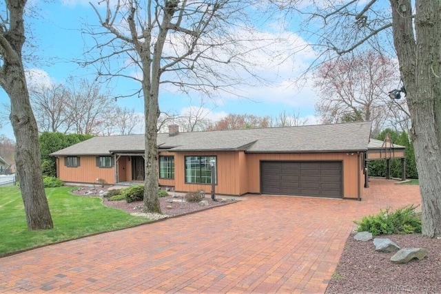single story home with a chimney, an attached garage, decorative driveway, and a front yard