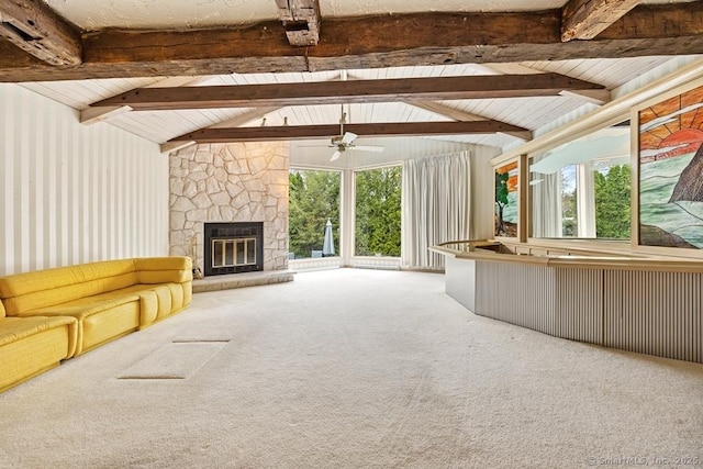 unfurnished living room featuring a stone fireplace, carpet flooring, ceiling fan, and lofted ceiling with beams