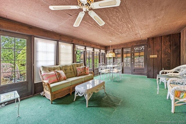 sunroom with wood walls, a healthy amount of sunlight, and carpet flooring