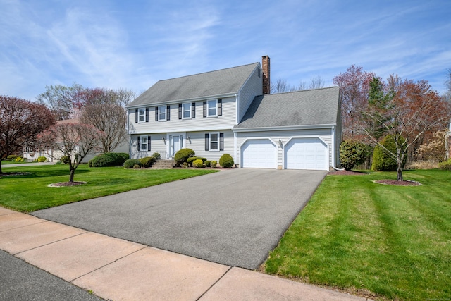 colonial inspired home featuring driveway, a chimney, a shingled roof, a front lawn, and a garage