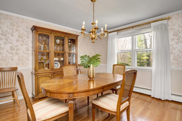 dining room with a chandelier, crown molding, a wainscoted wall, light wood-style flooring, and wallpapered walls