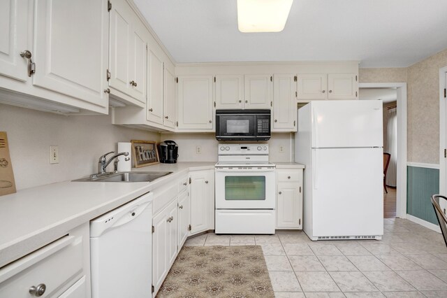 kitchen with light countertops, a sink, white cabinets, and white appliances