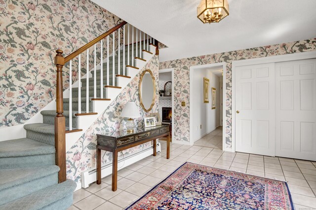 entryway featuring a baseboard heating unit, stairs, light tile patterned floors, and wallpapered walls