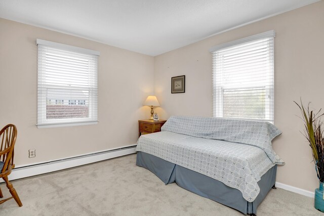 bedroom featuring a baseboard heating unit, multiple windows, and carpet flooring