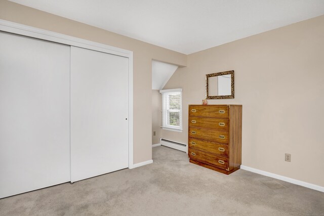 carpeted bedroom with vaulted ceiling, baseboards, a baseboard heating unit, and a closet