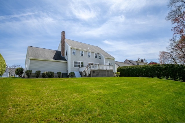 back of house featuring a lawn, a chimney, and a wooden deck