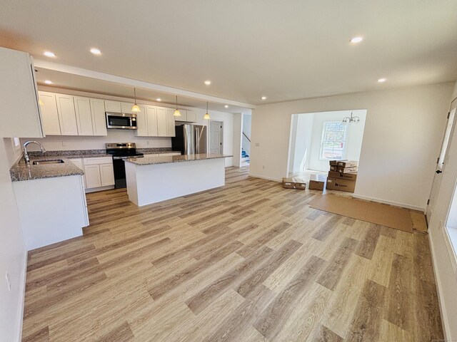 1 First St, Thompson, CT 06255 - kitchen featuring appliances with stainless steel finishes, a sink, white cabinetry, light wood-type flooring, and a center island