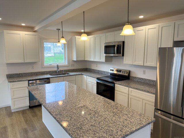 1 First St, Thompson, CT 06255 - kitchen with stainless steel appliances, a sink, a center island, light stone counters, and light wood-style flooring