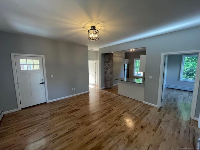 57 Erwin Pl, New Britain, CT 06051 - unfurnished living room featuring a baseboard radiator, a chandelier, wood finished floors, and baseboards