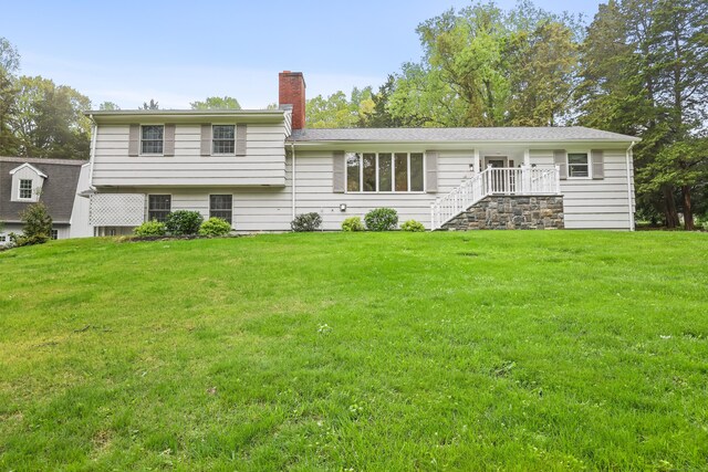 back of house featuring a lawn and a chimney