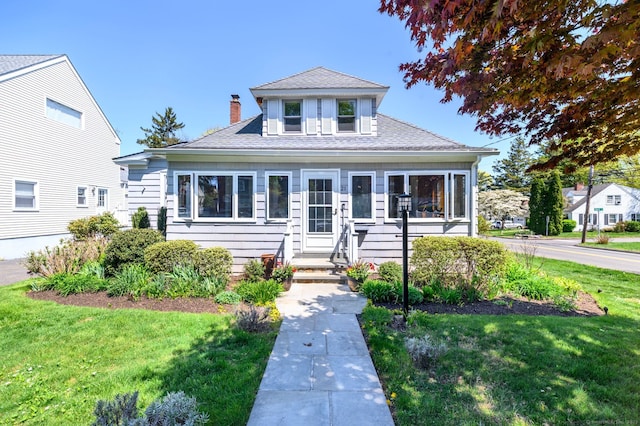 bungalow with roof with shingles, a chimney, and a front yard