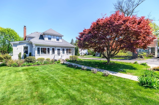 view of front of home with a chimney and a front yard