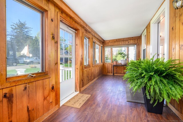 unfurnished sunroom with wooden walls, baseboards, and wood finished floors