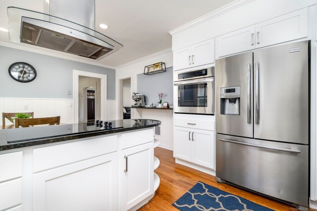 kitchen with crown molding, dark stone countertops, white cabinets, light wood-style flooring, and appliances with stainless steel finishes
