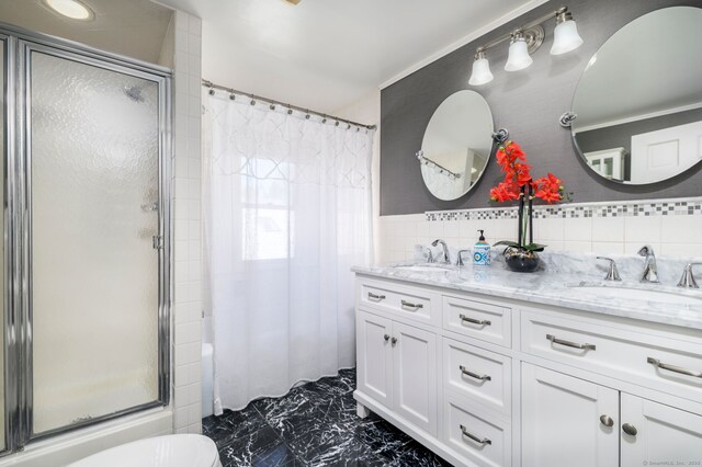 full bath with a sink, marble finish floor, and a shower stall